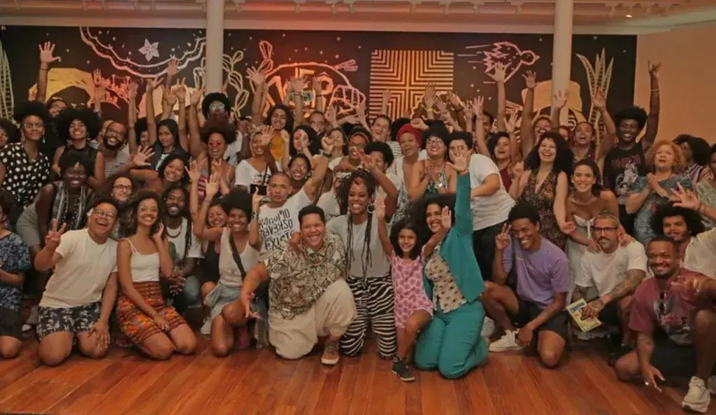 Grupo de pessoas celebrando em ambiente interno, com parede decorada.