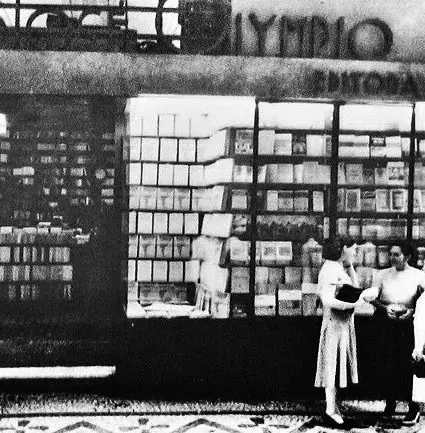 Livraria preto e branco com estante, vitrine e pessoas observando livros.