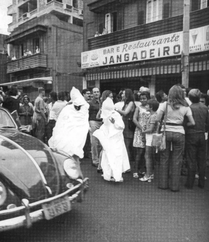 Rua movimentada com bar e restaurante "Jangadeiro" e pessoas reunidas.