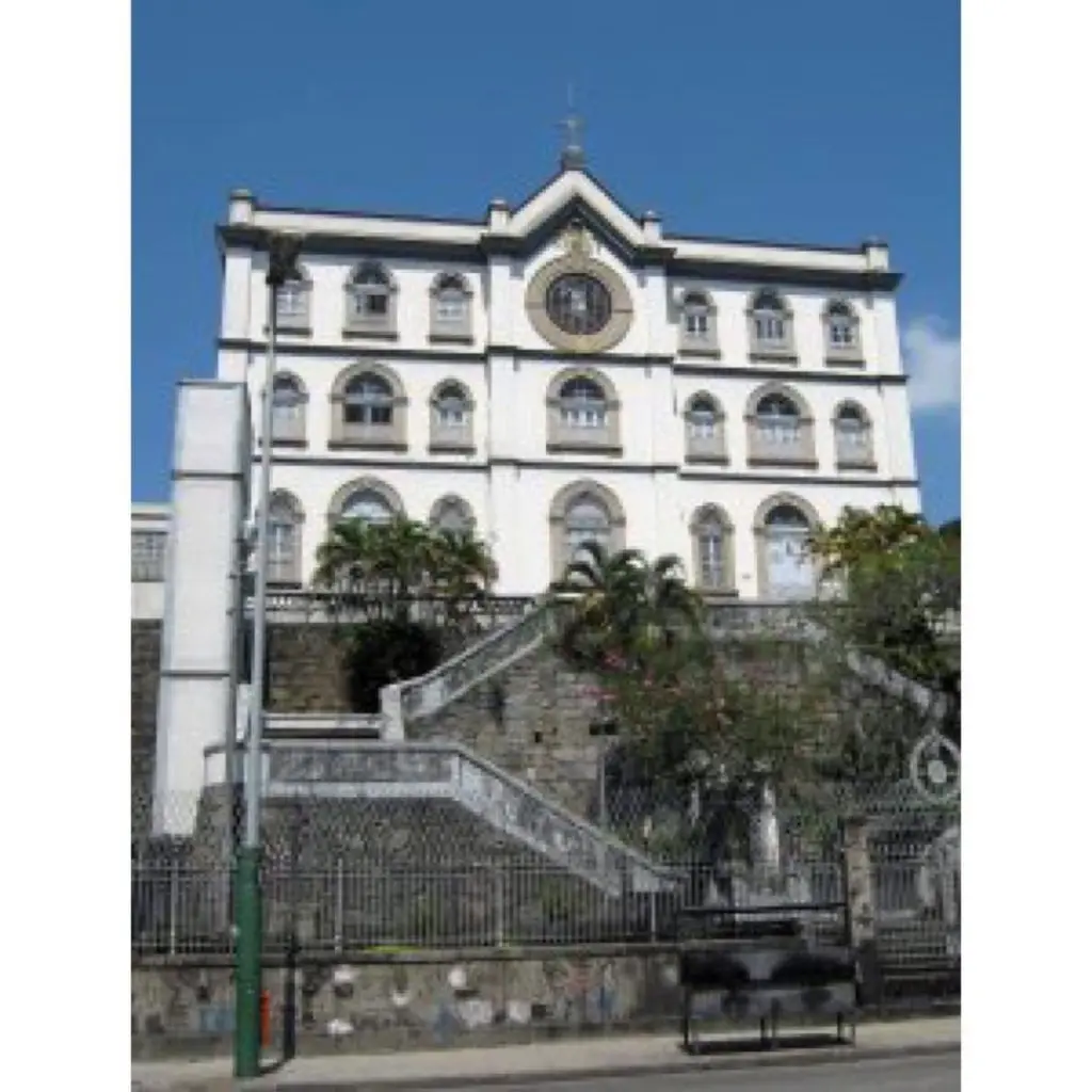 Edifício histórico com arquitetura clássica, escadaria de pedra e céu azul claro.