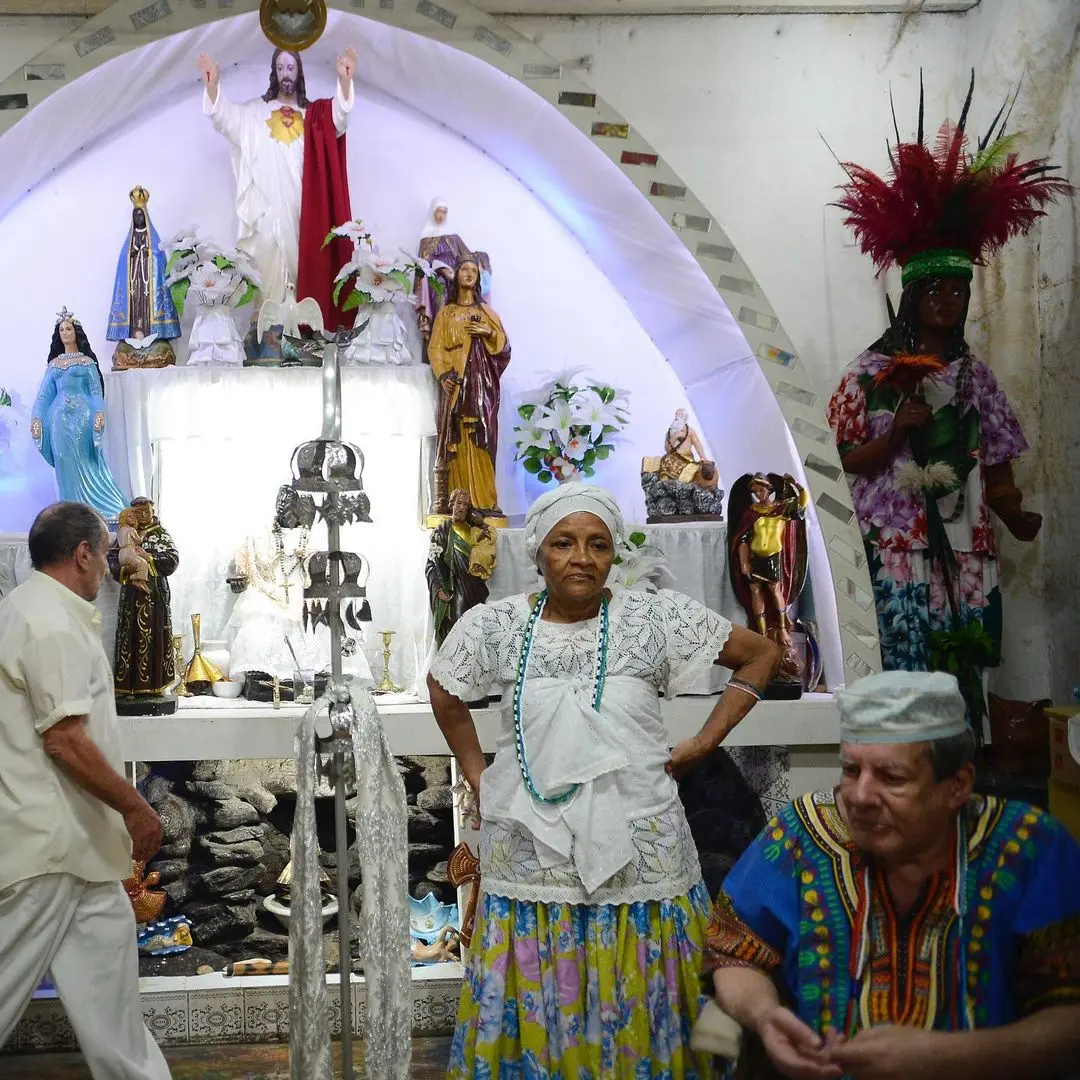 Altar religioso com imagens de figuras femininas e masculinas, Jesus Cristo e uma mulher com coroa de penas.