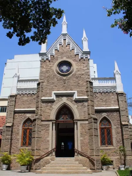 Igreja metodista com fachada gótica e entrada com porta de madeira e vidros coloridos.