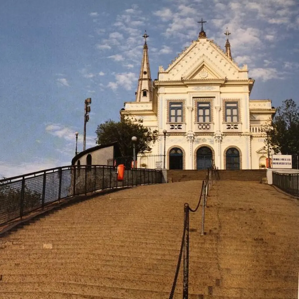 Igreja elevada com escadaria de pedra e fachada clara.