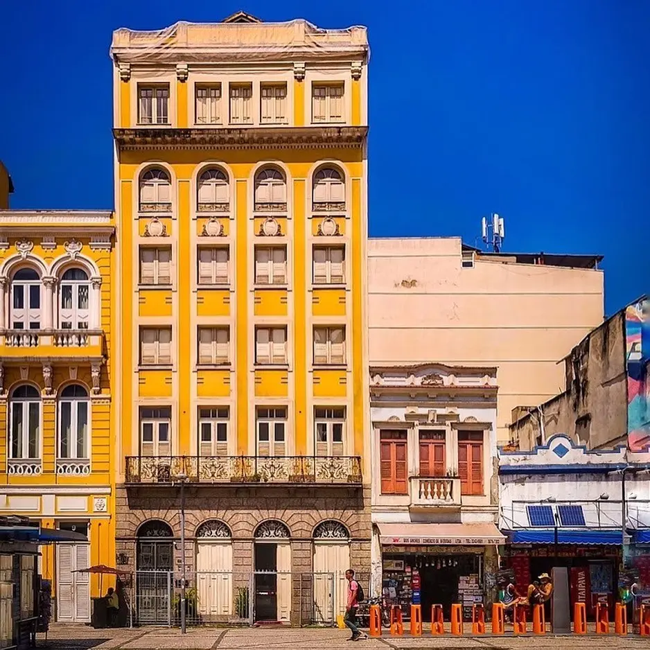 Cena urbana com edifícios históricos e pessoas caminhando.