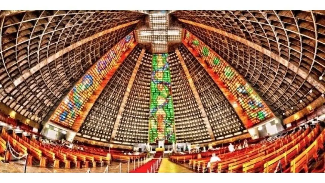 Interior da Catedral Metropolitana do Rio de Janeiro, com cúpula arredondada e bancos de madeira.