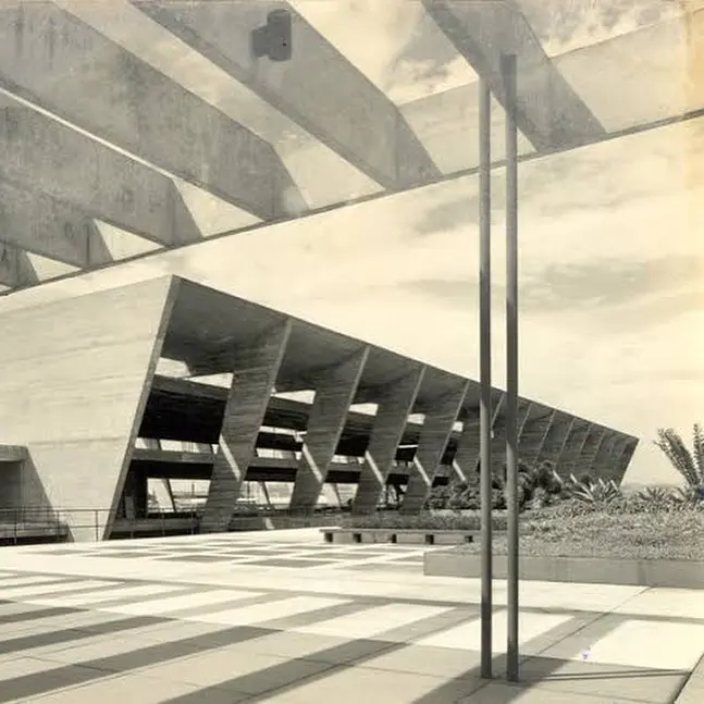 Edifício modernista com estruturas geométricas e entrada central.