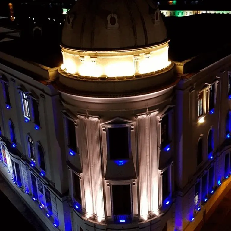 Edifício noturno com cúpula iluminada, fachada azul e "Centro Cultural dos Correios".