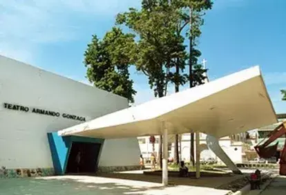 Teatro moderno com fachada branca e telhado inclinado.