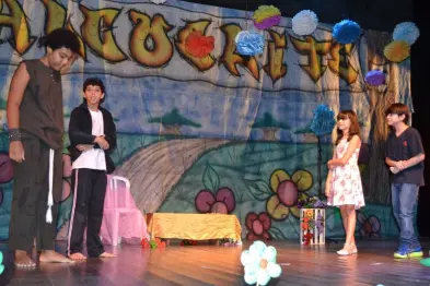 Espetáculo teatral com personagens e cenário colorido.