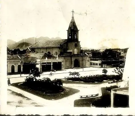 Uma praça histórica com igreja centralizada e arquitetura clássica ao lado.