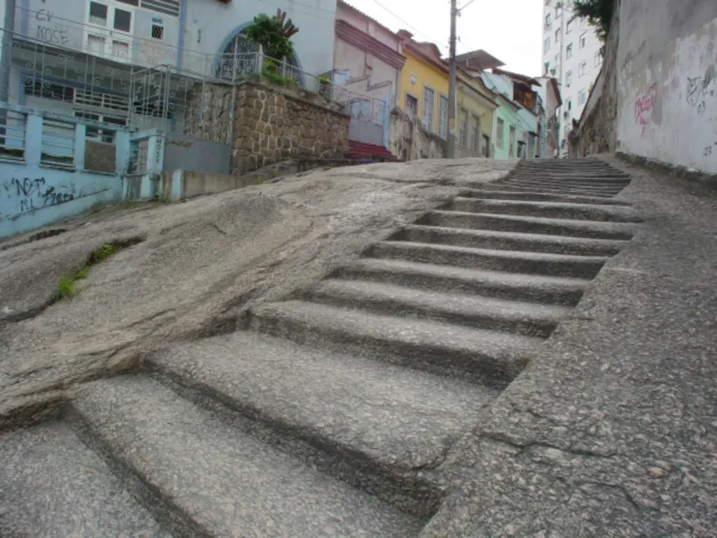 Uma rua com escadas de pedra, edifício azul e casas coloridas em colina.