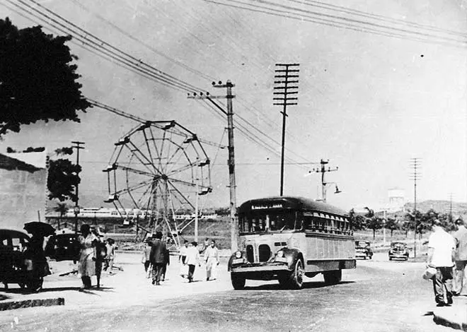 Parque de diversões com roda-gigante e ônibus antigo.