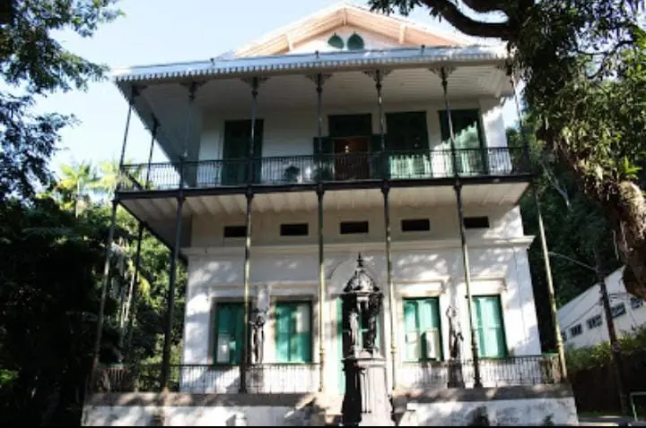 Edifício histórico em ambiente verdejante com detalhes em verde.