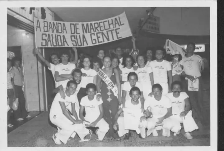 Banda de música em preto e branco, sorrindo e posando para foto.