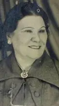 Uma mulher sorridente em casaco com capuz e colar, fundo com padrões geométricos.