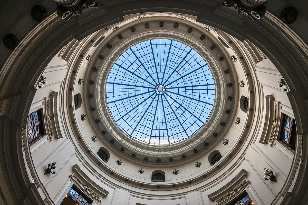 Cúpula metálica com abertura circular, iluminada por luz natural.