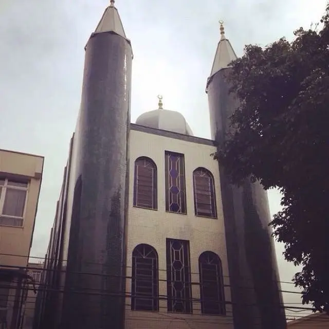 Mesquita com torres altas e cúpulas, céu nublado ao fundo.