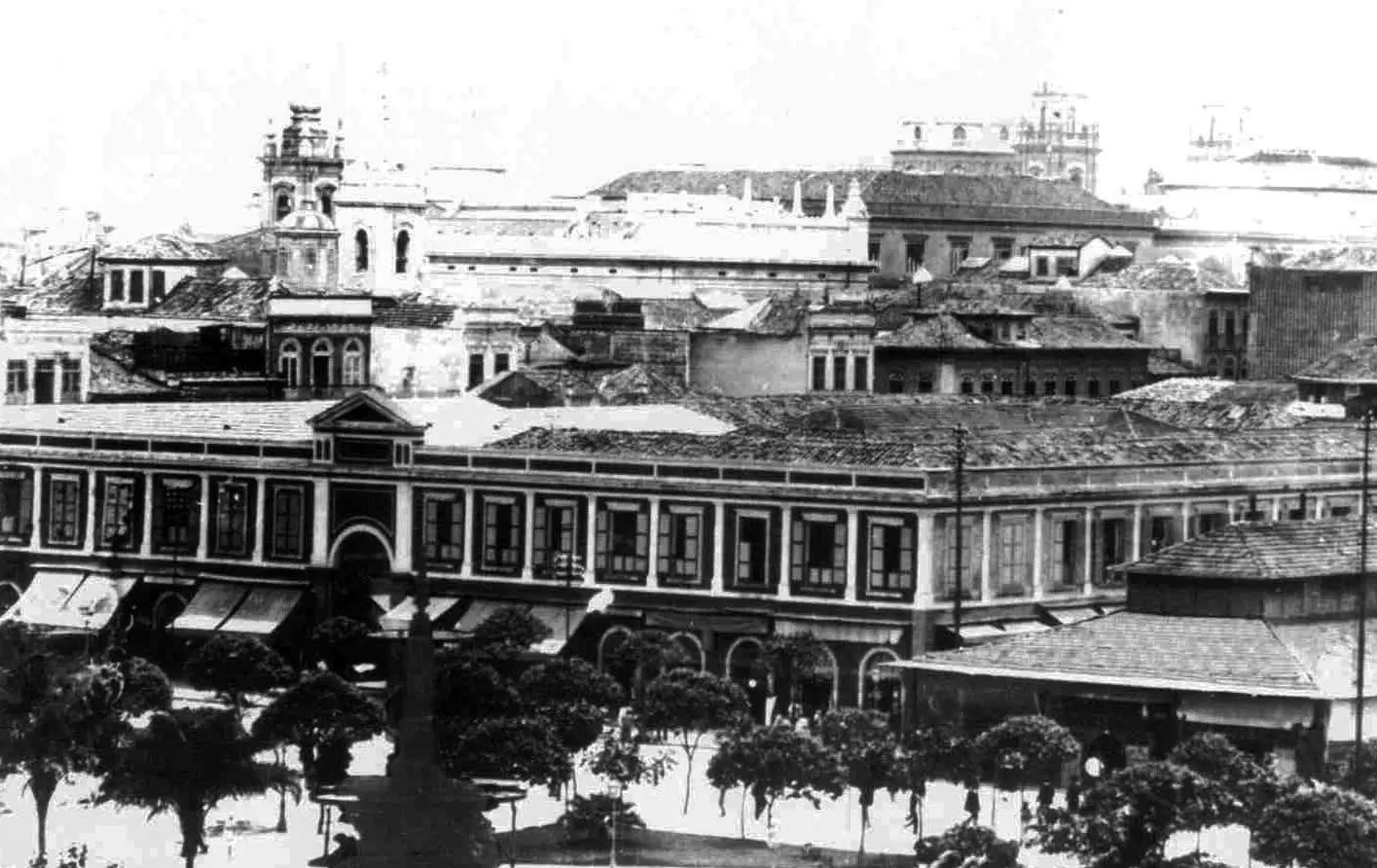 Mercado local em Candelária, Rio de Janeiro, com edifícios e torre sineira.