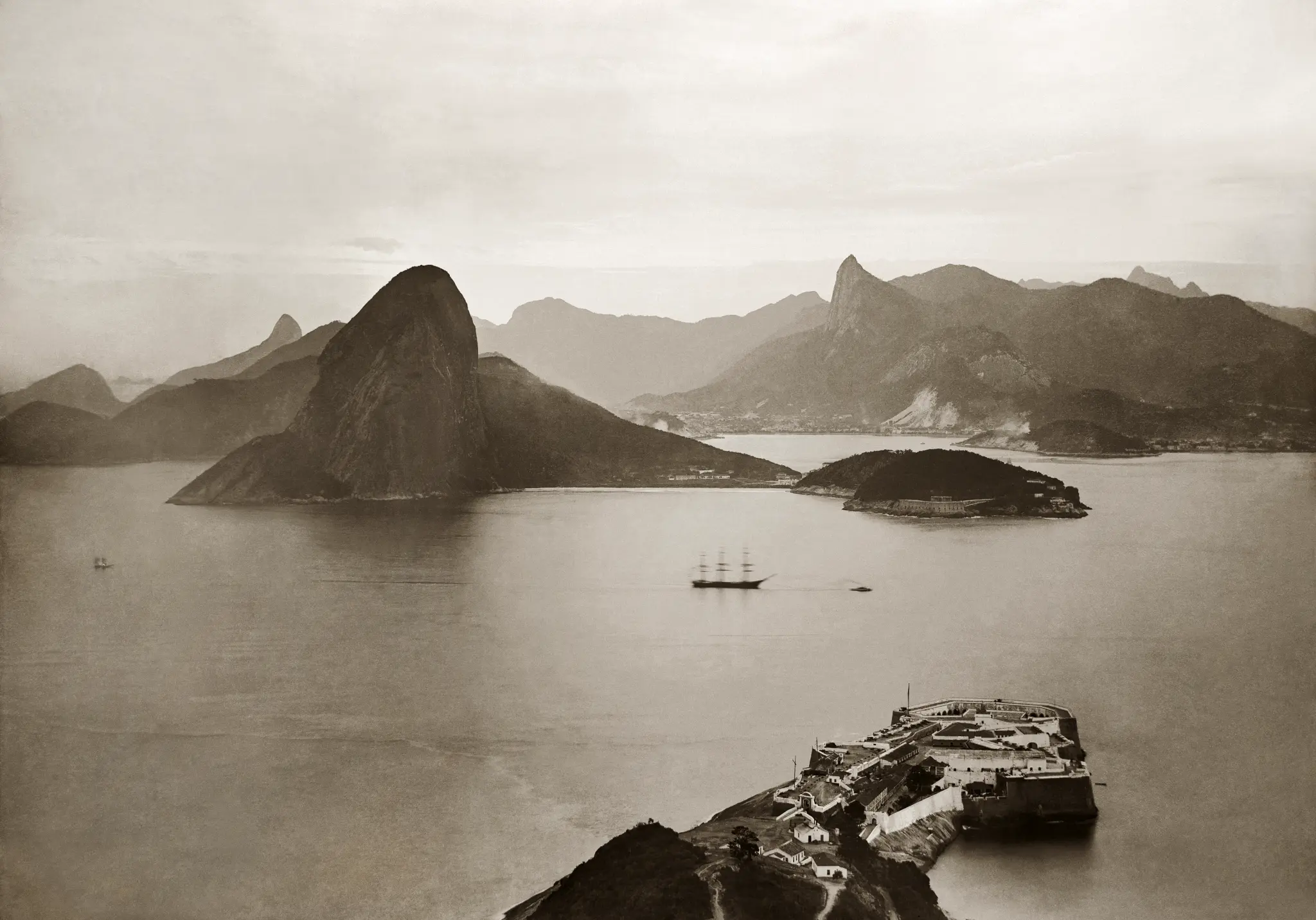Imagem antiga da Baía de Guanabara com montanha do pão de açúcar, navio a vela e fortaleza.