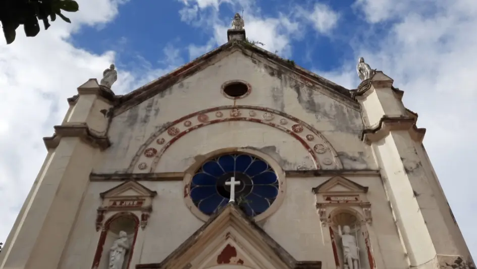Igreja com vitral azul e estátuas humanas.