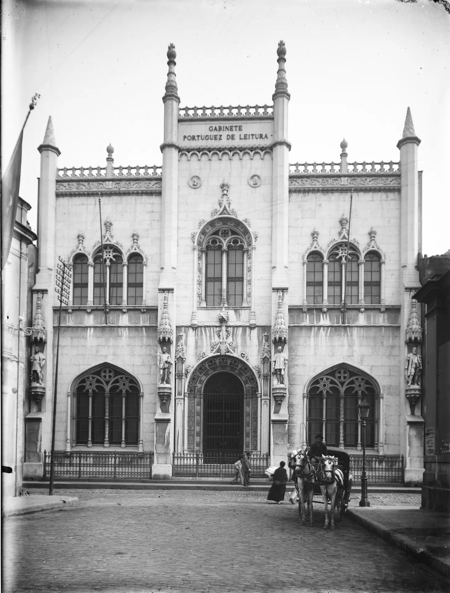 Edifício gótico com entrada fechada por grades, janelas arredondadas e leitura pública.