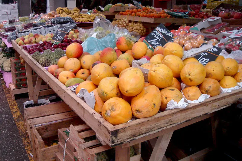 Mercado de frutas com variedade de itens em caixas e mesas.