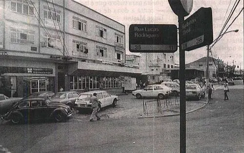 Cruzamento urbano com sinais de trânsito e prédios comerciais.