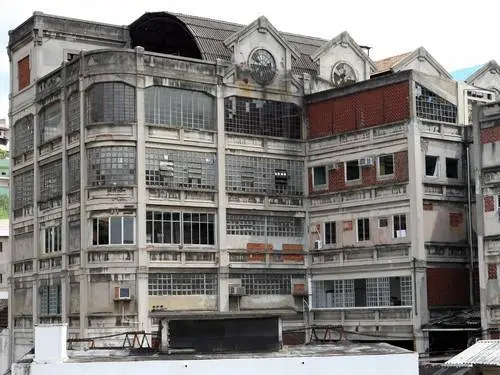 Fábrica abandonada com fachada em destaque, céu azul claro ao fundo.