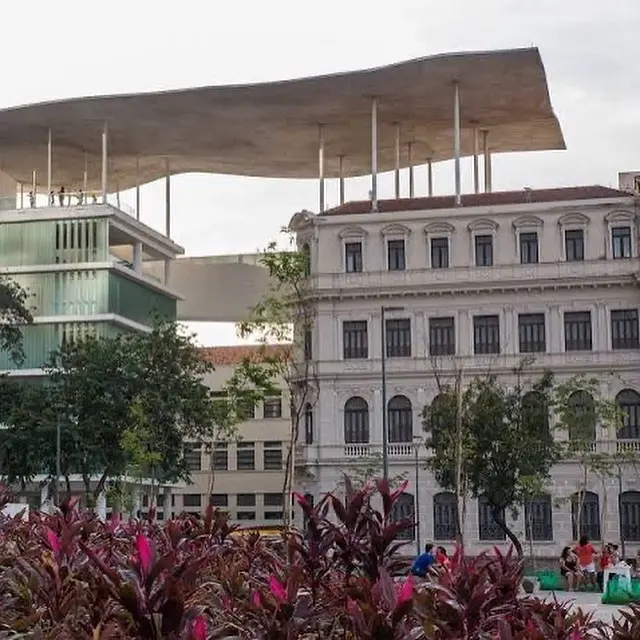 Museu com edifícios modernos e clássicos, plantas coloridas e céu nublado.