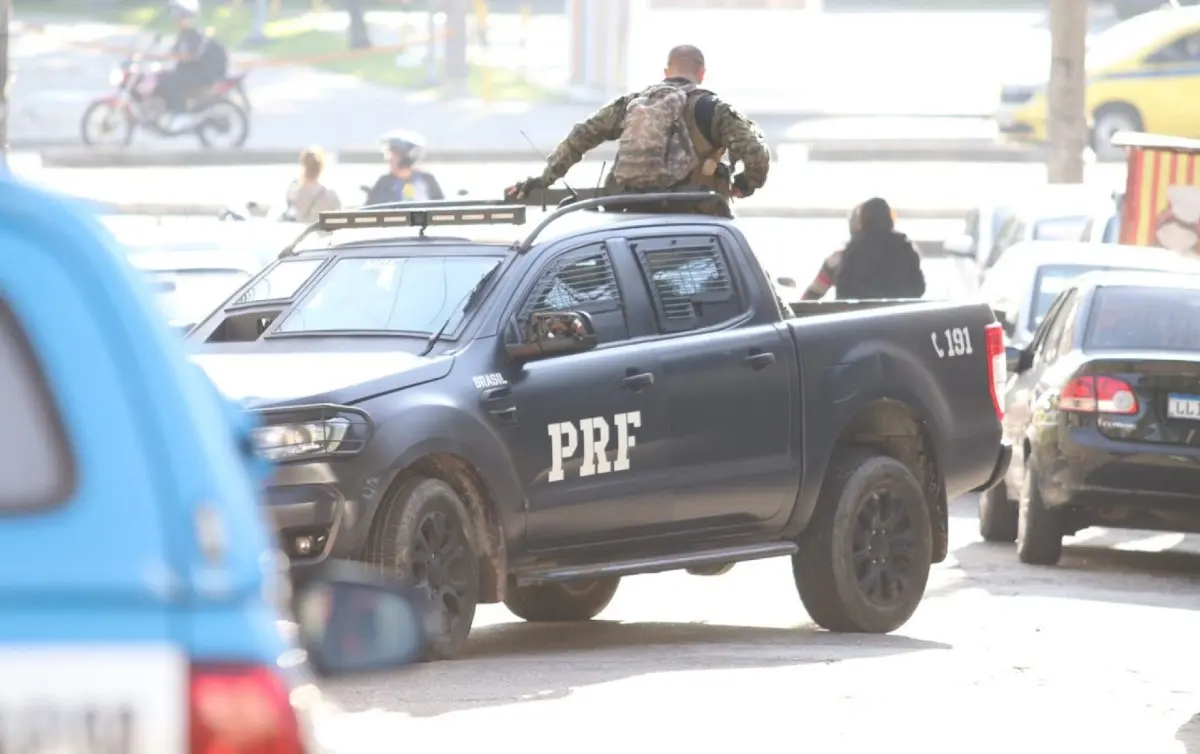 Veículo policial da PRF em movimento, militar no teto.