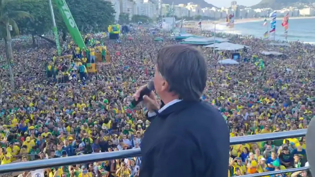 Pessoas em roupas amarelas e verdes em praia costeira durante evento político.