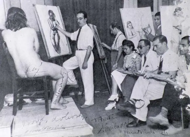 Aula de arte com modelo feminino nu e professor explicando.