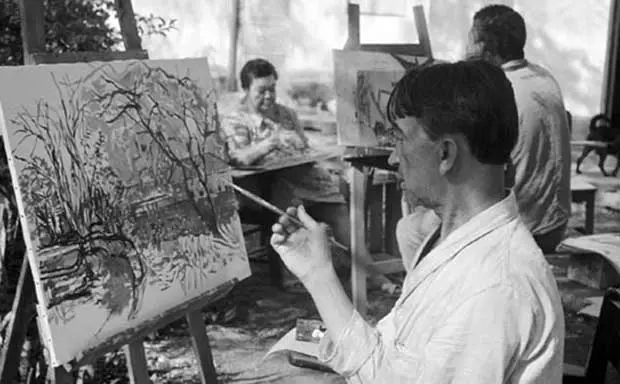 Ateliê de arte com dois artistas trabalhando em quadros.