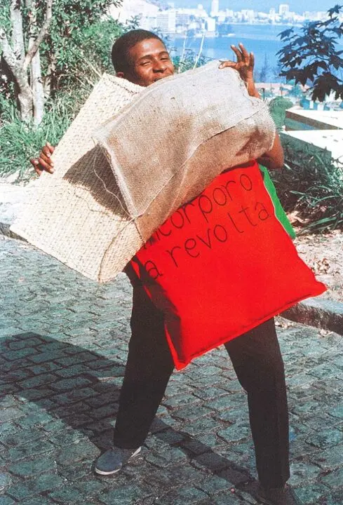 Homem sorrindo segurando objetos em fundo verde.