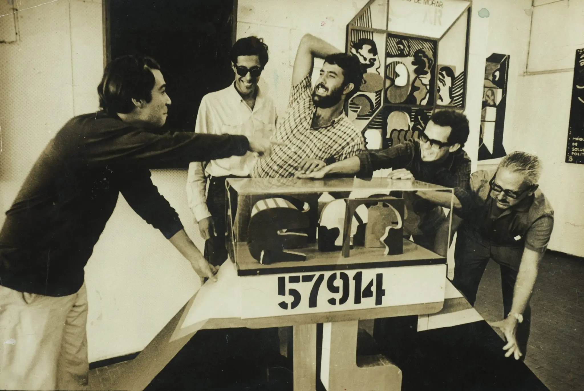 Grupo de homens em torno de uma mesa num painel decorativo.