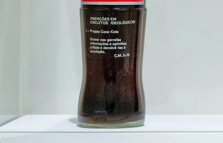 Garrafa de Coca-Cola com etiqueta vermelha e branca em fundo branco.