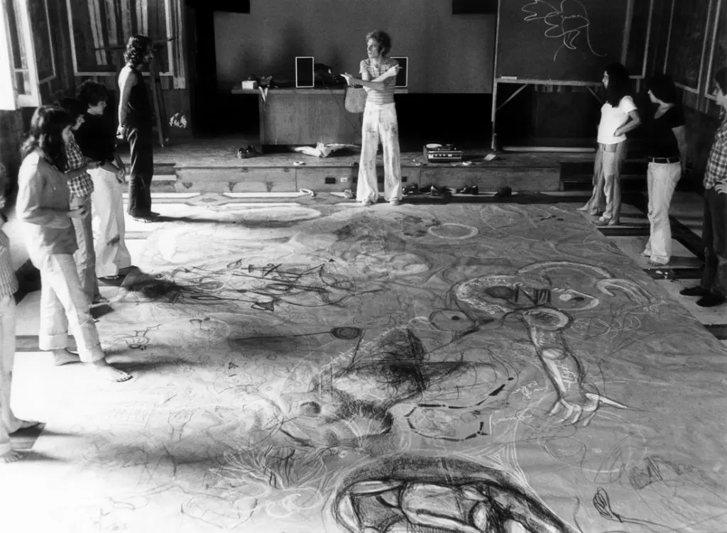 Grupo de pessoas em sala de arte observando desenho complexo.