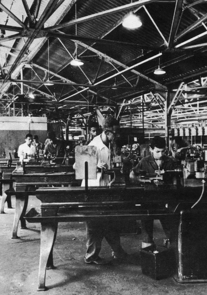 Trabalhadores em fábrica industrial, preto e branco.