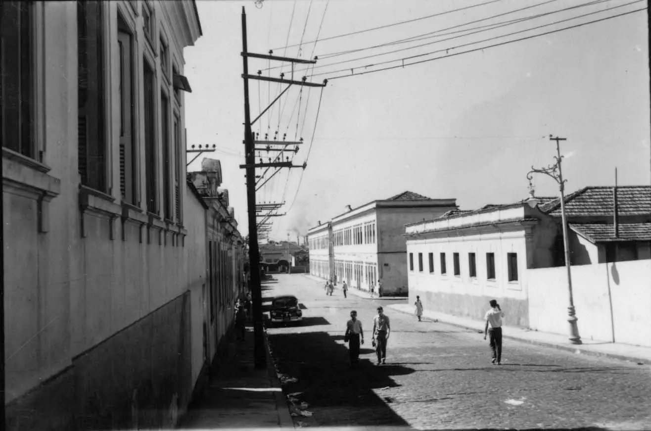 Rua urbana com edifícios e pessoas caminhando.