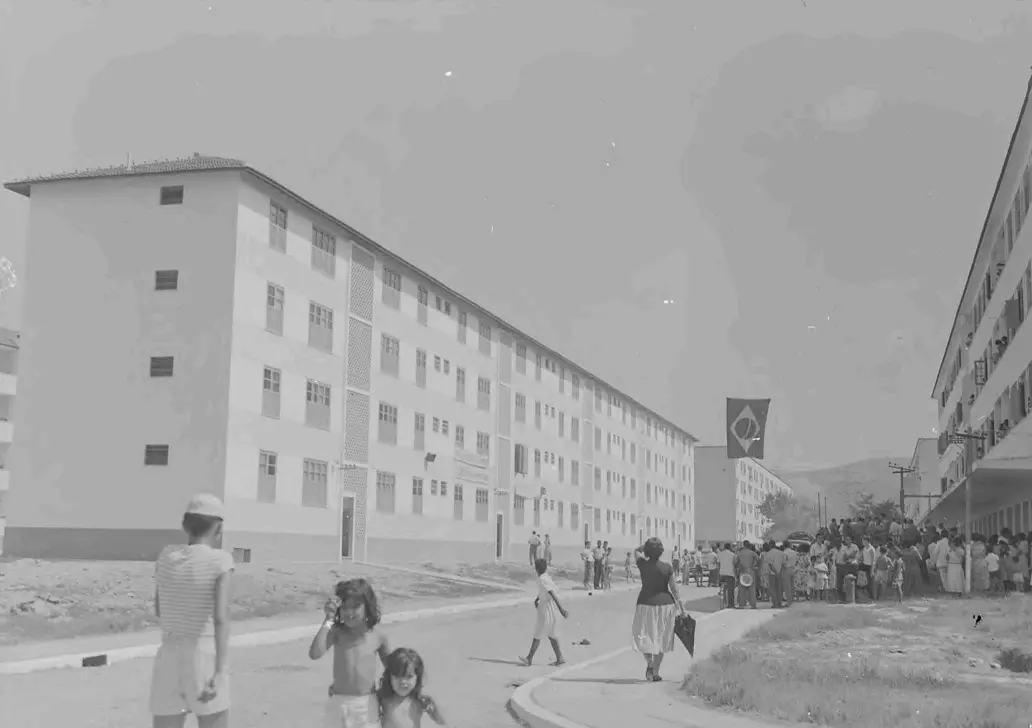 Edifícios residenciais em preto e branco, com pessoas caminhando.