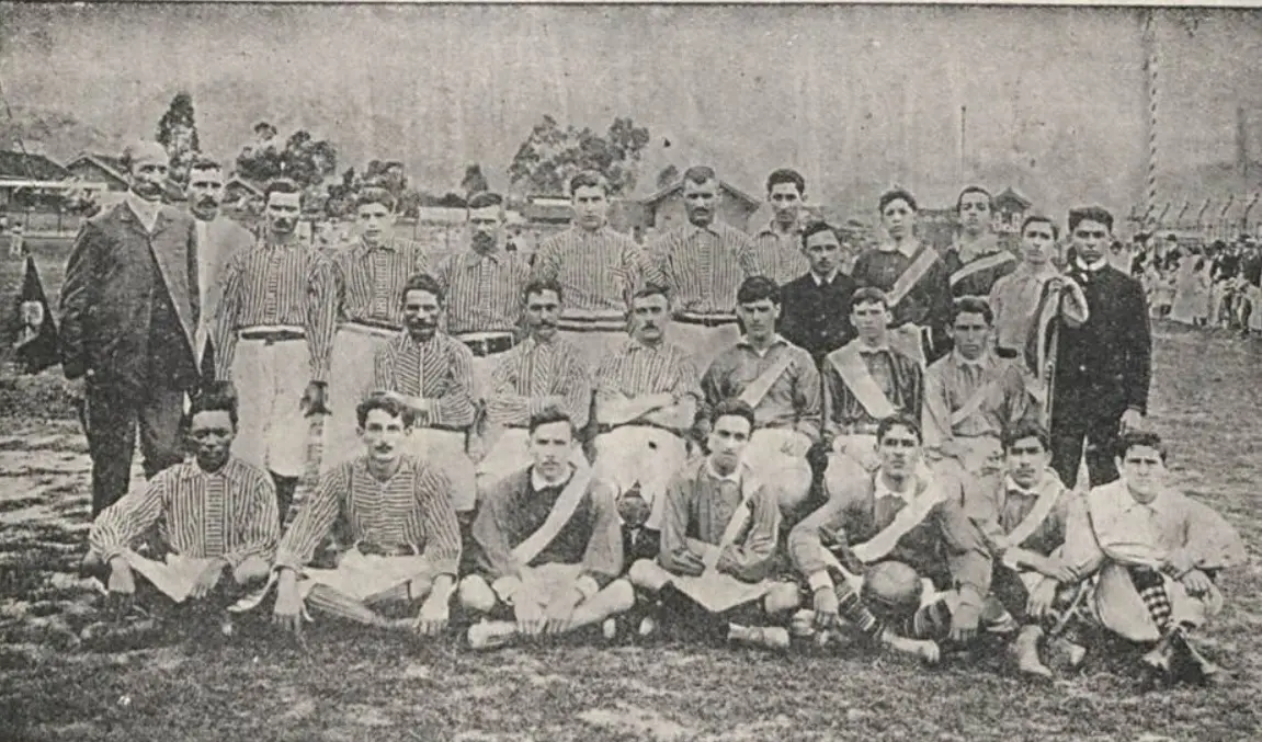 Grupo de pessoas em campo gramado, provavelmente de futebol.
