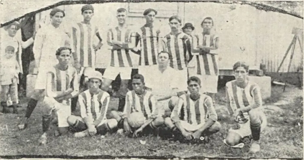 Grupo de pessoas em preto e branco, possivelmente jogadores de futebol, posando para foto.