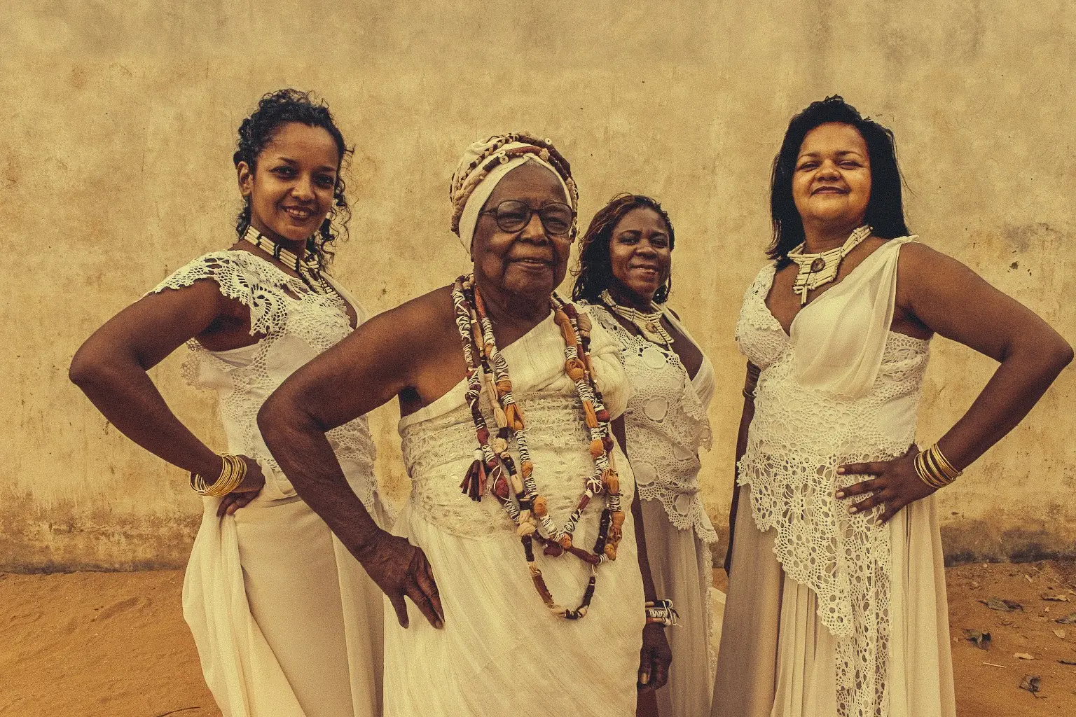 Quatro mulheres em vestidos brancos posando juntos.