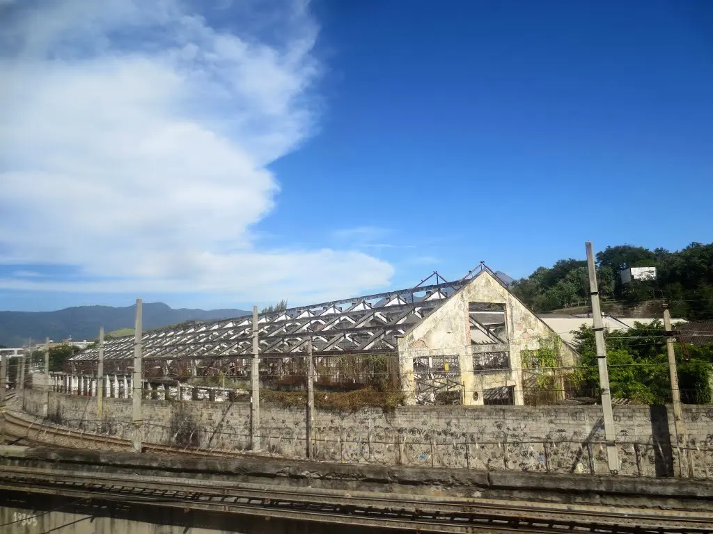 Fábrica industrial abandonada com grafites e trilhos ferroviários.