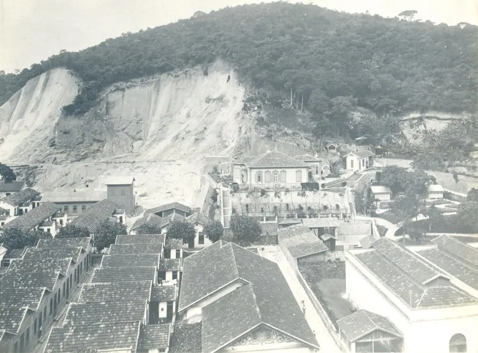 Cidade em preto e branco com casas e colina.