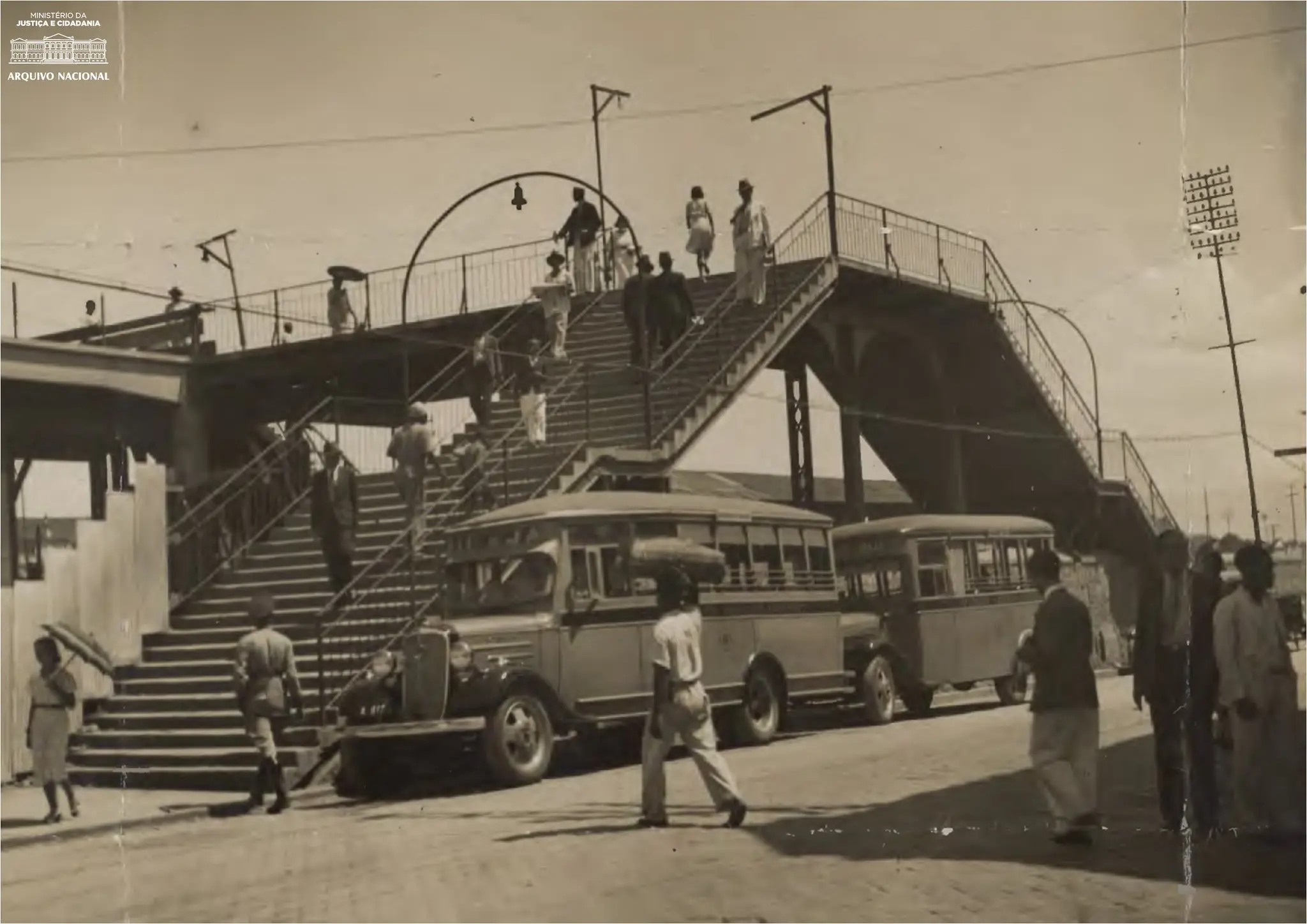 Cena urbana antiga com edifício, escadaria, ônibus e pessoas.