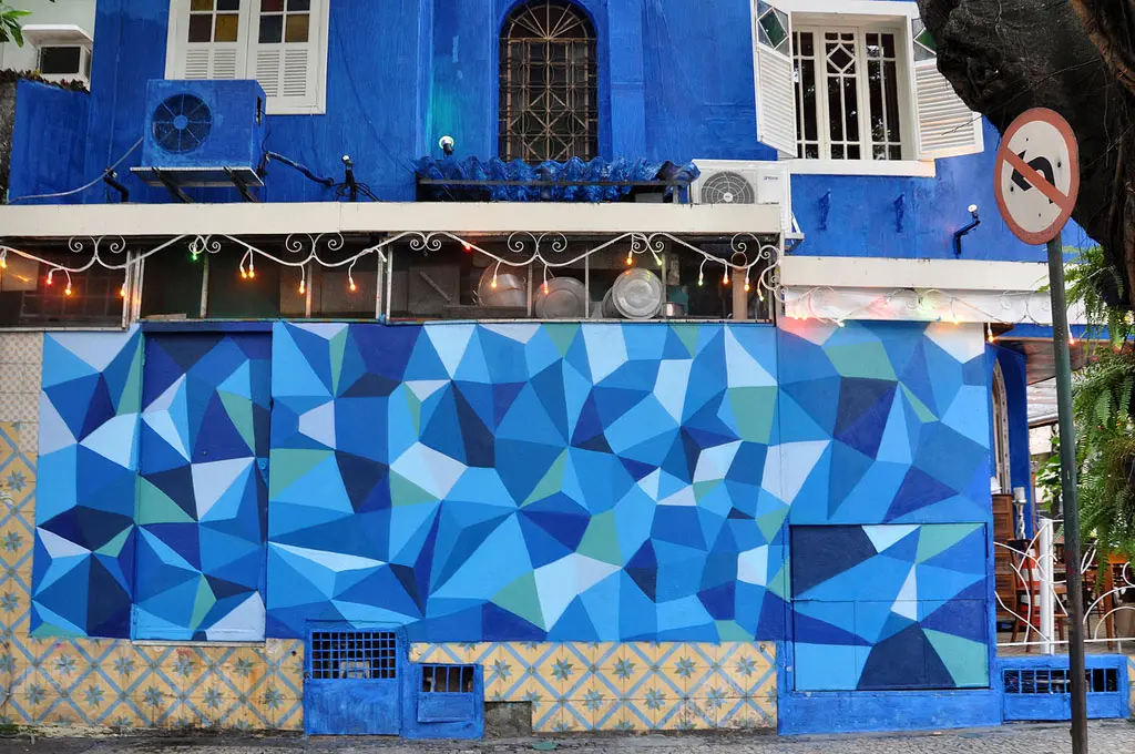 Edifício com grafite, fachada azul vibrante, placa de sinalização de proibição de estacionamento.