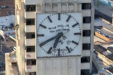 Relógio monumental em torre urbana, com inscrição "NOSSA PAÍS ESTÁ ONDE SOMOS AMADOS".