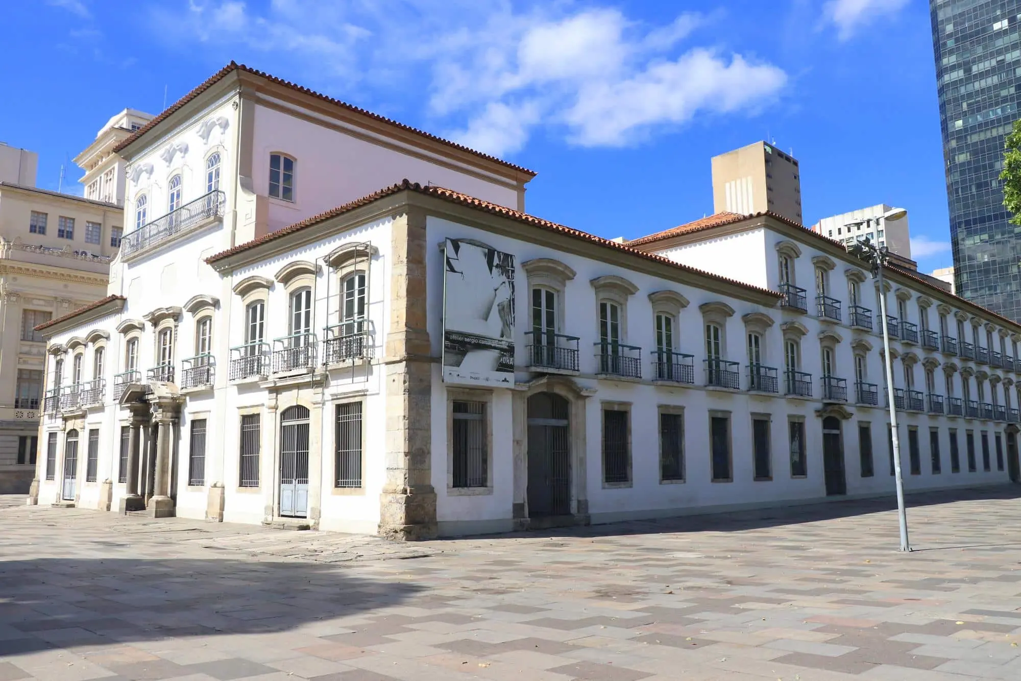 Edifício histórico em cidade, colunas antigas e fachada branca.