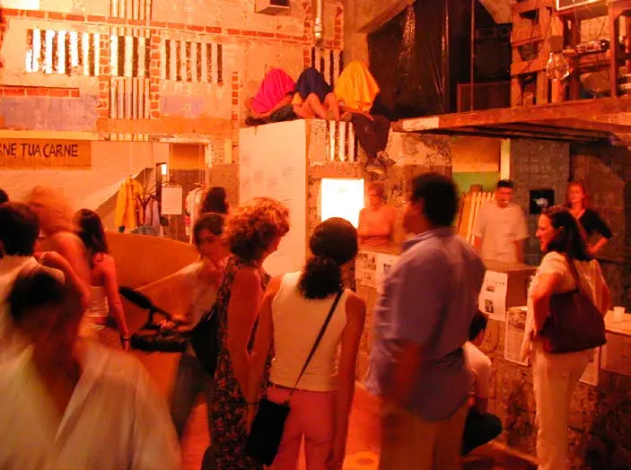 Exposição de arte contemporânea com visitantes e artefatos visíveis.